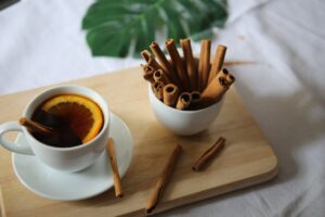 Cozy setup with cinnamon sticks and warm orange tea on a wooden surface.