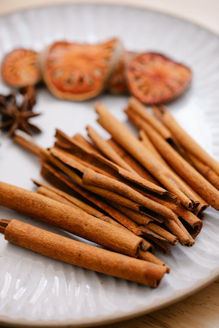 Close-up of cinnamon sticks with dried fruits and spices on a plate, perfect for food photography.